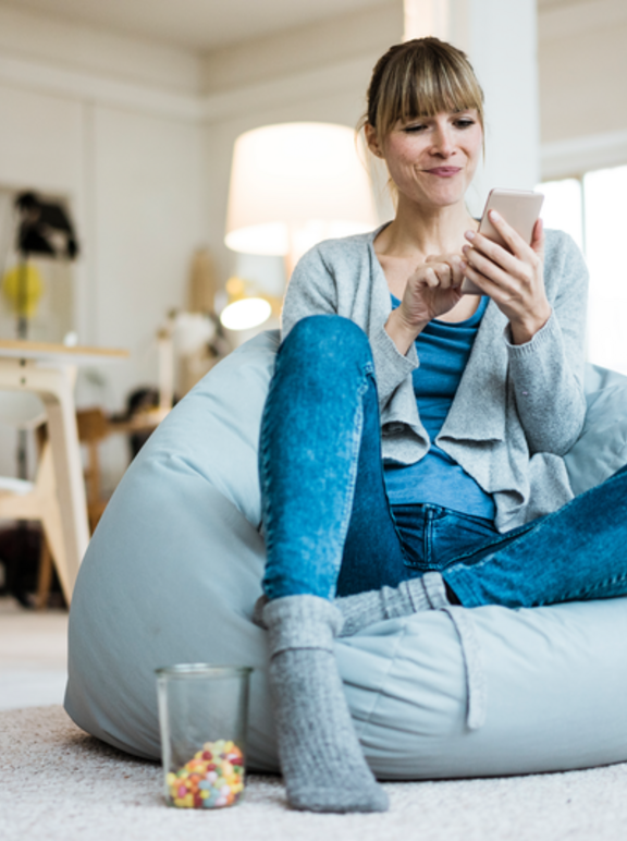 Smiling woman sitting in beanbag using cell phone